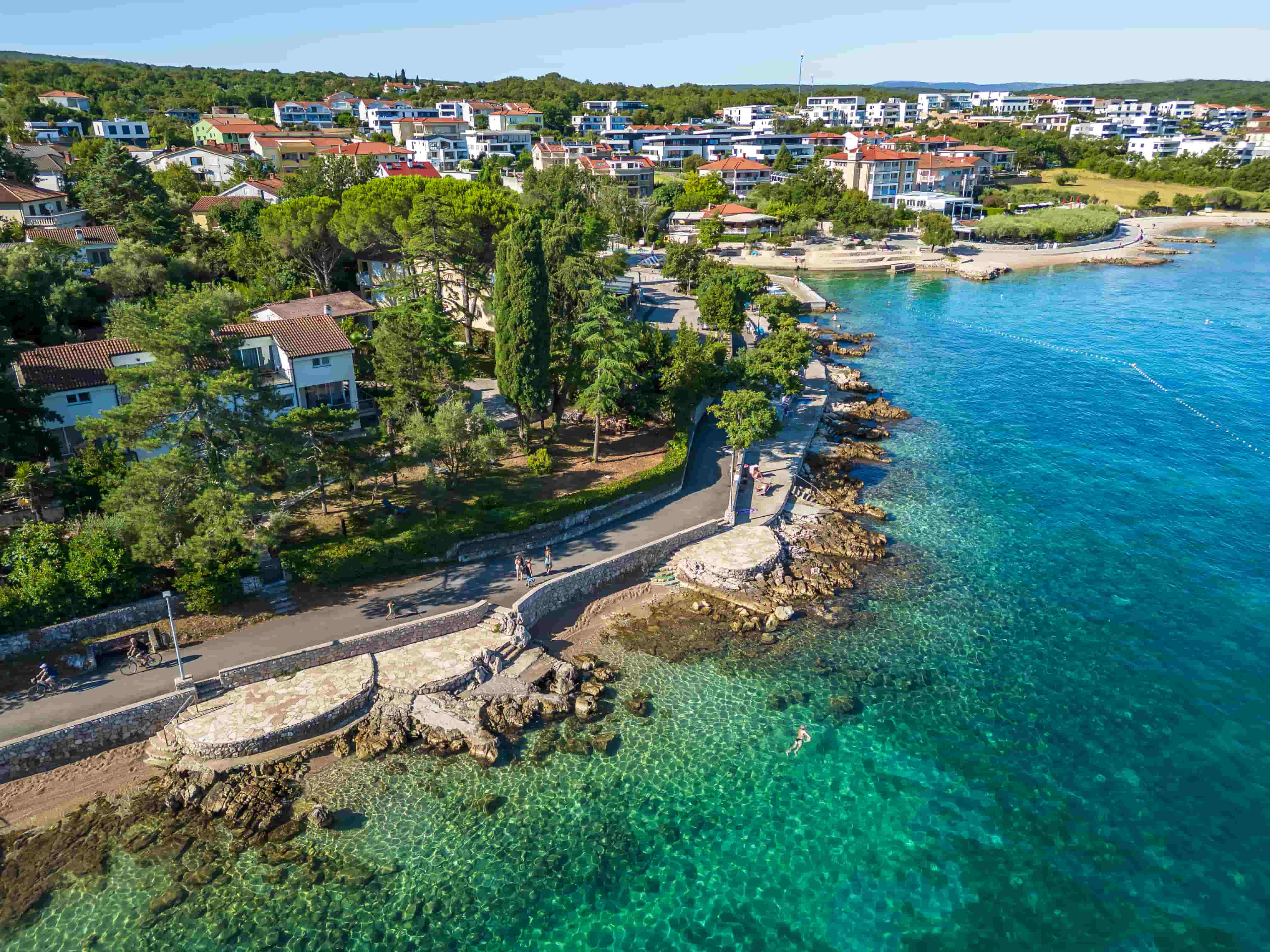 Aerial view of Cuklićevo Beach on Krk island with turquoise sea, seaside promenade, and costal villas