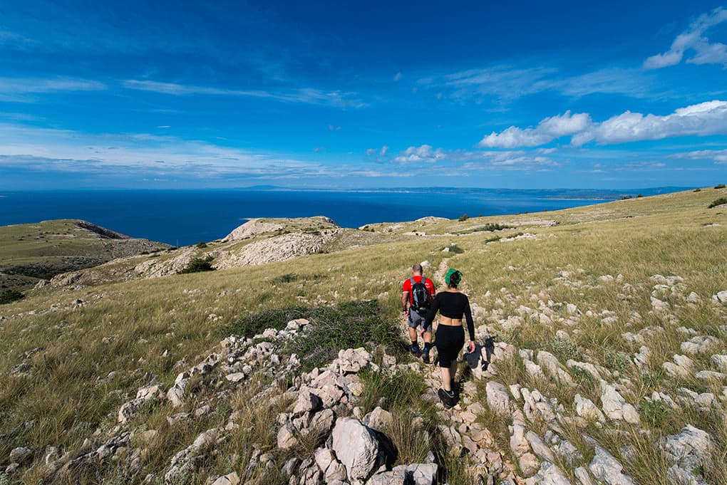 Hikers on a rocky trail above the Adriatic Sea on Krk Island