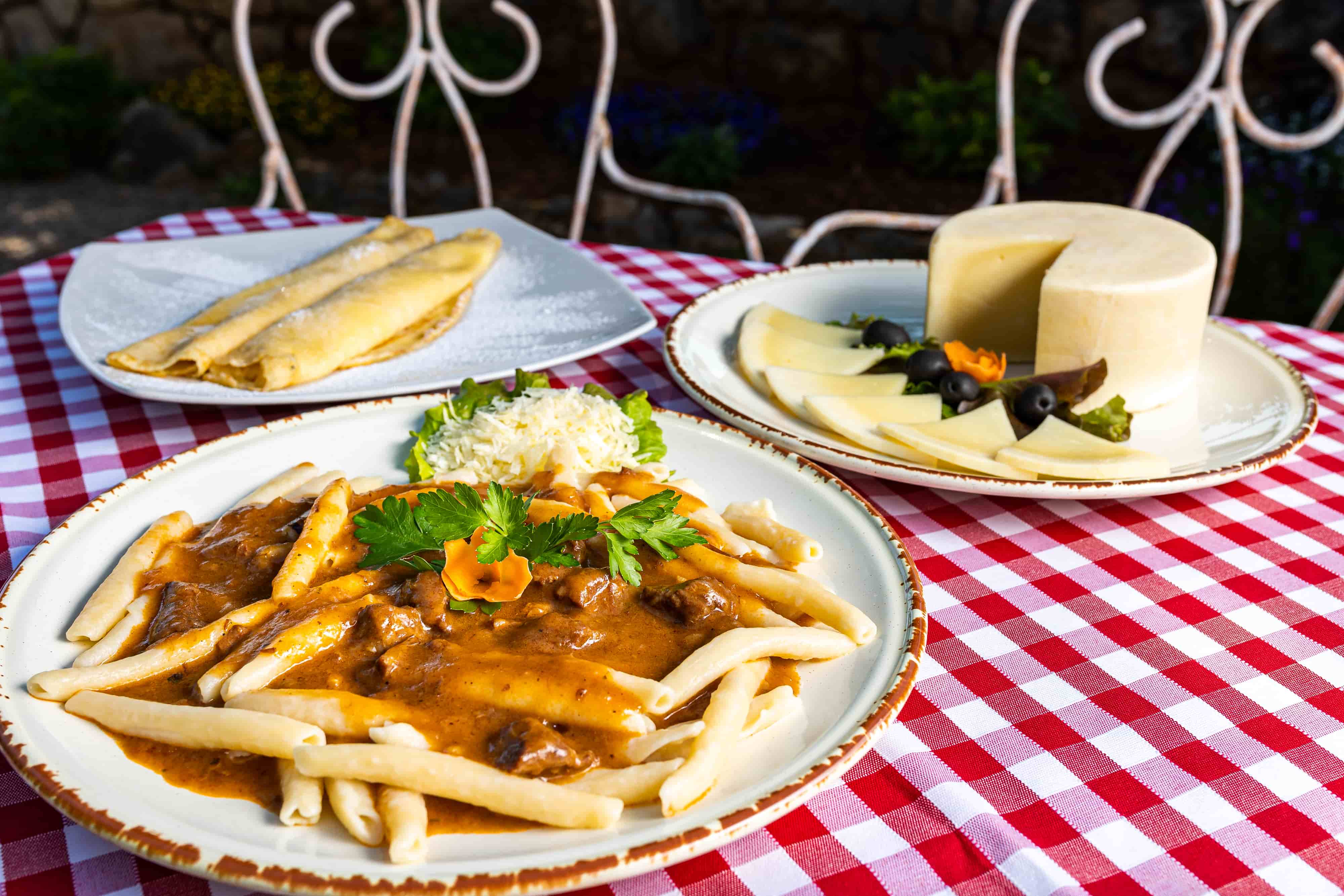 Traditional Krk island dishes with šurlice pasta, pancakes, skuta, and homemade cheese on a checkered tablecloth