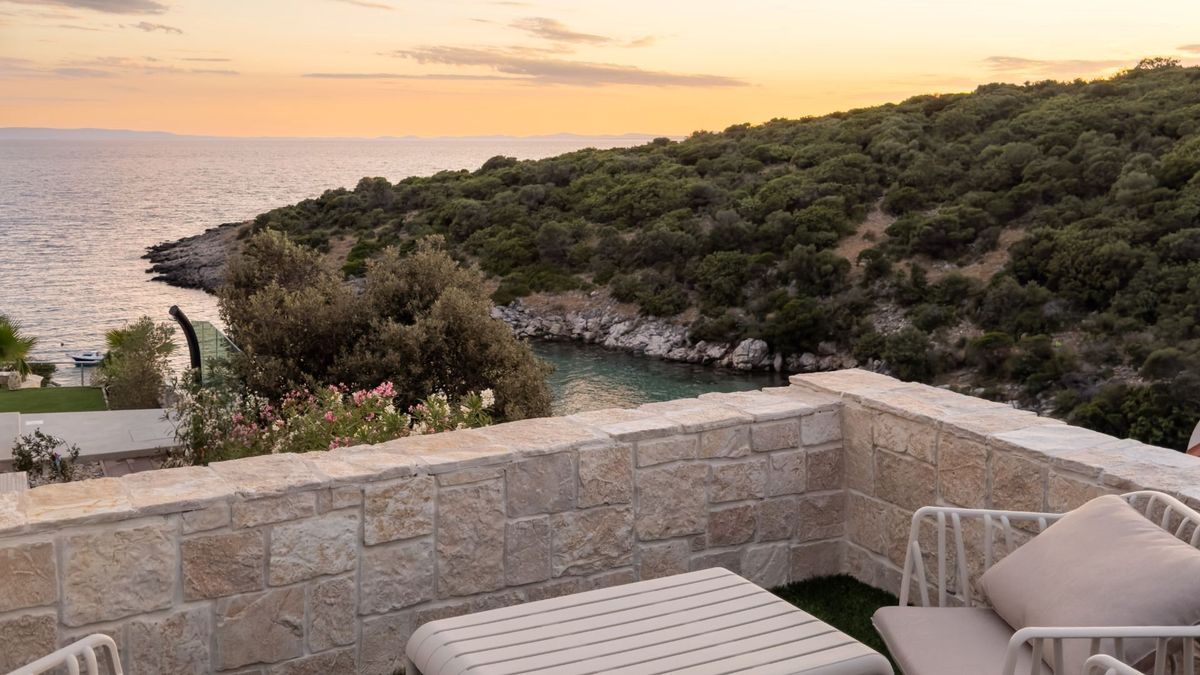 Stone terrace in Villa Kukurina with seating area overlooking Adriatic bay at sunset