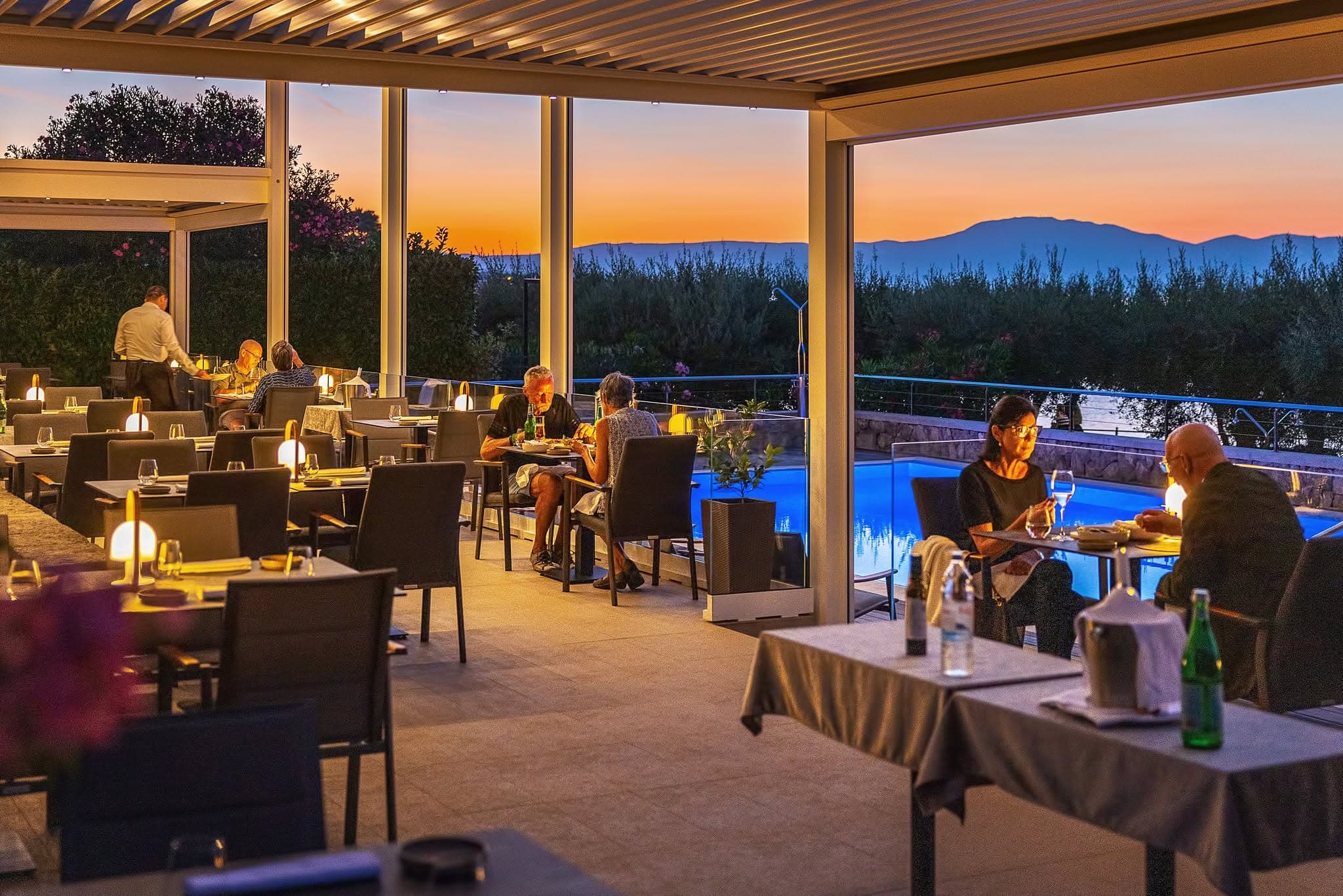 Villa Rova restaurant terrace in Malinska with guests dining at sunset beside the pool