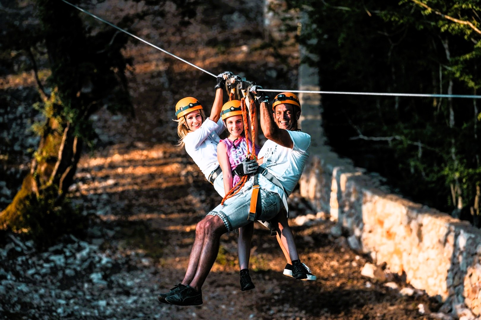Three people ziplining together